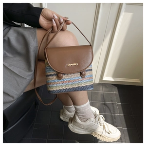 Detail of rainbow woven straw bag with brown leather flap and adjustable strap