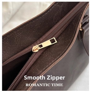 Close-up of smooth gold metal zipper and vintage brown textured leather handbag