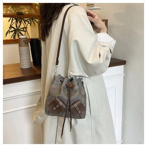 Detail of canvas bucket bag with brown leather drawstring and metal eyelets on gray fabric