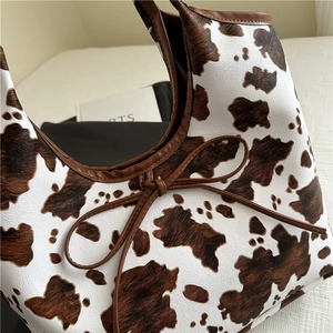 Borsa tote con stampa mucca, finiture in pelle marrone e fiocco in un layout elegante