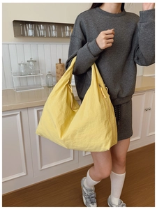 Detailed view of the bright yellow nylon tote bag with wide shoulder straps on model