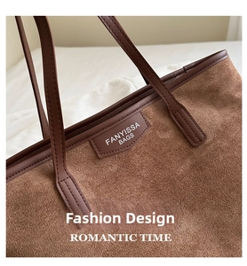 Close-up of brown suede tote bag featuring leather straps and brand logo patch detail