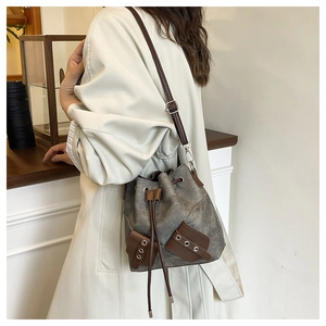 Detail of canvas drawstring bucket bag with leather trim and adjustable crossbody strap
