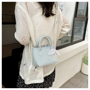 Close-up of light blue mini bag with litchi texture and lace pearl bow charm