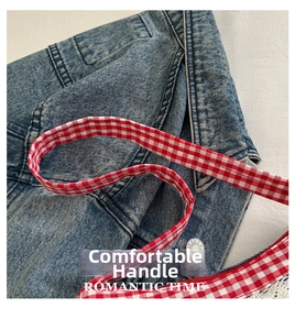 Close-up of blue denim bag with silver JEANS button and red gingham strap detail