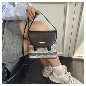 Détail d'un sac seau tissé à rayures avec rabat en cuir noir et logo métallique doré