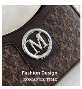 Detailed macro view of the silver M logo buckle and monogram texture on brown shoulder bag