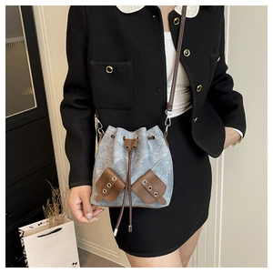 Detailed view of canvas bucket bag with brown leather drawstring and metal eyelets