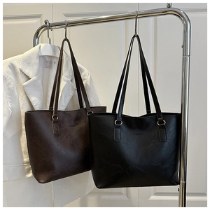 Dettaglio di borse tote minimaliste in pelle marrone e nera con finitura strutturata e logo