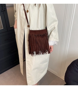 Detailed view of brown suede crossbody bag with long tassels and thin shoulder strap