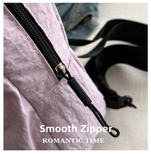 Detail of smooth metal zipper and black rubber drawstring on lavender nylon bag