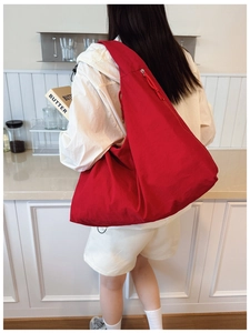 Back view of a large red canvas tote bag shown on a model in a kitchen setting