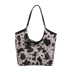Chic cow print tote bag with black bow detail and slim shoulder straps for summer