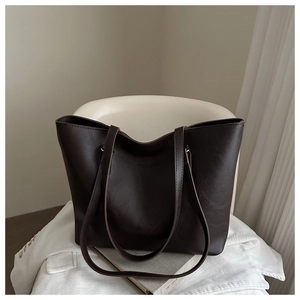 Detail of dark brown tote bag showing natural leather texture and embossed logo
