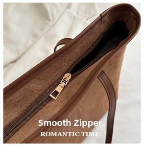 Close-up of smooth gold-tone zipper closure on a brown suede tote bag for women