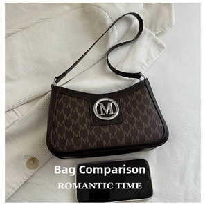 Detail view of brown vintage baguette bag with letter print next to a smartphone