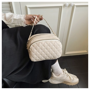 Dettaglio della borsa trapuntata beige con zip dorata e tracolla in pelle a catena