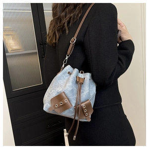 Detailed side view of vintage denim bucket bag with brown leather drawstring and strap