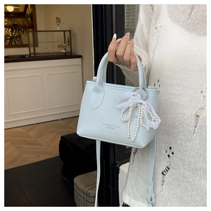 Close-up of light blue handbag featuring lychee texture and pearl lace bow charm