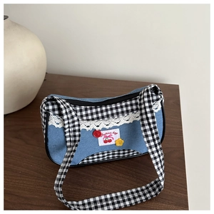 Detailed shot of denim checkered handbag featuring lace edges and cherry embroidery patches