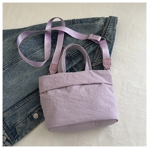 Detail of lavender purple pleated nylon bucket bag on denim and white textured fabric