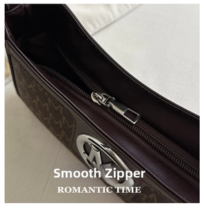 Macro detail of dark brown monogram handbag featuring a smooth silver metal zipper and hardware