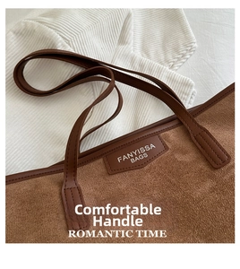 Detail of caramel suede tote bag featuring a leather logo patch and stitched handles