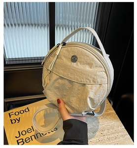Detailed close-up of nylon round crossbody bag with metal M-logo and zip closure