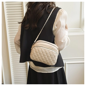 Detail of beige quilted leather crossbody bag with dual zippers and gold chain strap