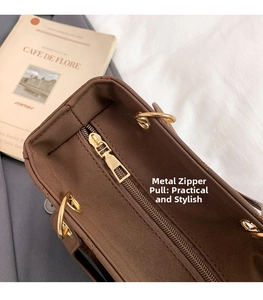Dettaglio ravvicinato della borsa marrone scuro con cerniera in metallo dorato e gancio