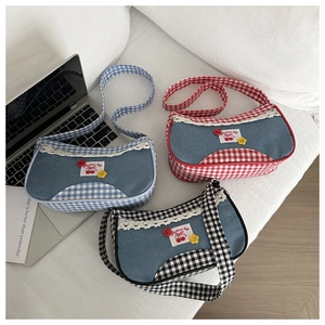 Flat lay detail of denim shoulder bags with plaid trim, white lace and cherry patches