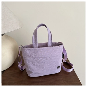 Detail view of light purple nylon bucket bag with Fantissa logo on a wooden surface