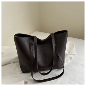 Detailed close-up of dark brown leather tote bag with embossed fashion text texture