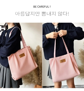 Detail of pink corduroy tote bag showing textured fabric and leather logo patch