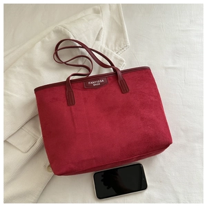 Top view of large red suede tote bag with leather logo tag and smartphone for size scale