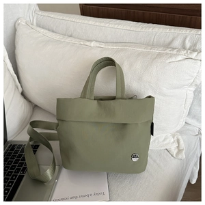 Olive green fabric bucket bag detail with wide shoulder strap and metal logo branding