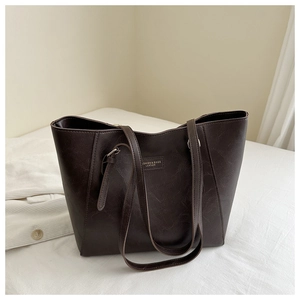 Close-up of dark brown tote bag showing its rich lychee texture and leather logo detail