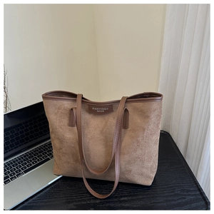 Detail view of a large brown suede tote bag featuring a leather strap for office commuting