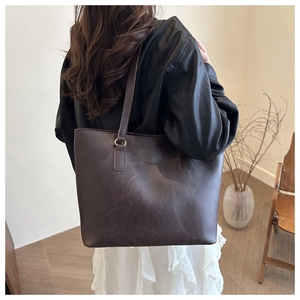 Detail of a large vintage brown tote bag in oil wax leather texture with logo embossing