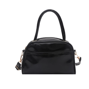 Minimalist black patent leather handbag with gold hardware and curved top handle design