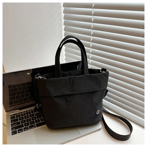 Detail of black pleated texture fabric and circular logo on kids crossbody bag