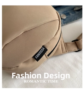 Close-up of khaki canvas texture and black logo label on a minimalist crossbody bag
