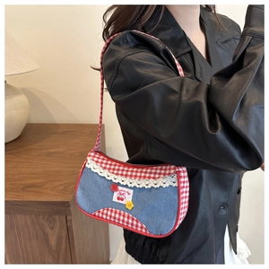 Detail of denim and red gingham patchwork bag with lace trim and cherry embroidery