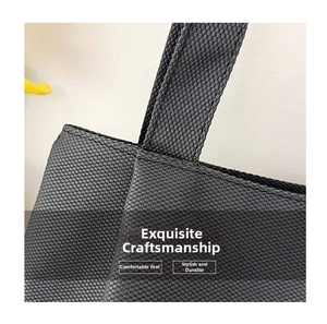 Close-up of neat stitching and reinforced handle on a black woven canvas tote bag