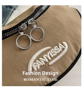 Detailed close-up of khaki dumpling bag with FANYISSA embroidery and silver ring zipper