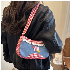 Detail of denim and red gingham shoulder bag with lace trim and cherry patch