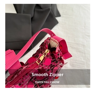Close-up of smooth gold metal zipper on pink sequined shoulder bag for women