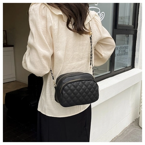 Detail shot of black quilted crossbody bag with gold chain strap and dual zippers