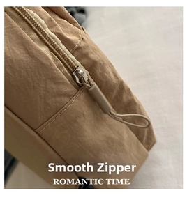 Detail view of smooth silver metal zipper and khaki nylon strap on fashion chest bag