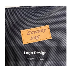 Detail of the brown faux leather brand patch with Cowboy bag embossing on black canvas